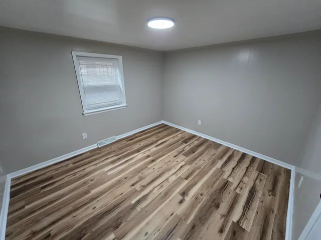 a view of a room with wooden floor and window