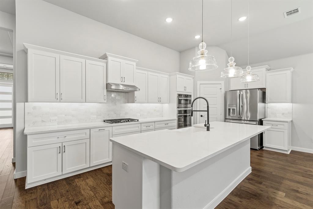 3311 Willena Road Melissa, TX 75454 - Photo 26 of 40 Contemporary kitchen featuring white cabinetry, a large center island with a black gooseneck faucet, stainless steel appliances, and wood-finish flooring