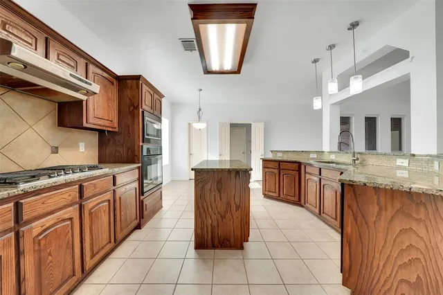 a kitchen with stainless steel appliances granite countertop a stove a sink and a refrigerator