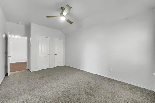 an empty room with a ceiling fan and a bathroom