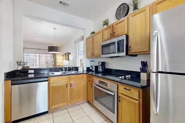 a kitchen with granite countertop a refrigerator stove top oven a sink and dishwasher