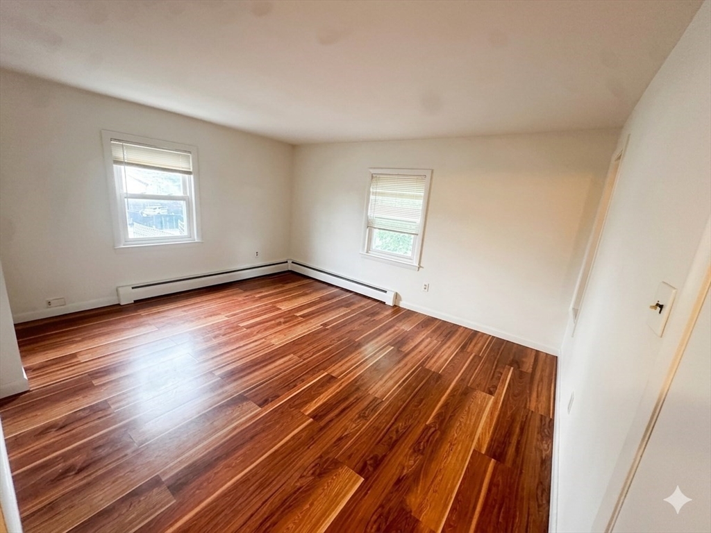 87 R Madison Street, Unit 2R Malden, MA 02148 - Photo 3 of 7 a view of an empty room with wooden floor and a window