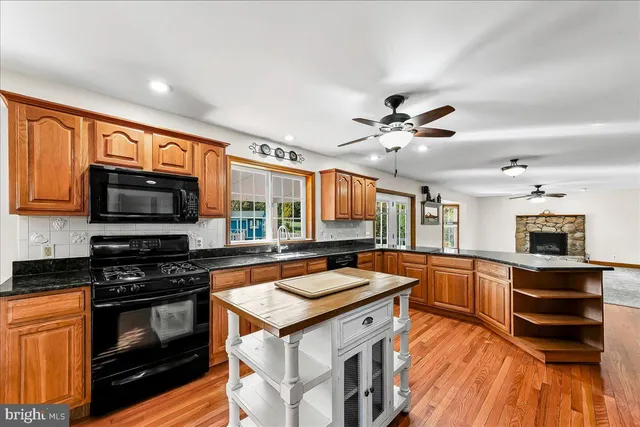a kitchen with stainless steel appliances granite countertop a stove a sink dishwasher and a dining table with wooden floor