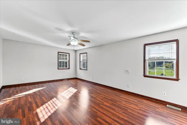 a view of an empty room with window and wooden floor