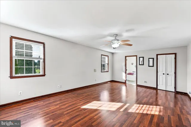 an empty room with wooden floor chandelier and windows