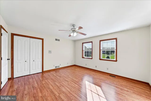 an empty room with windows and ceiling fan