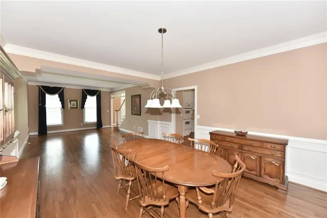 a dining room with wooden floor a chandelier a wooden table and chairs