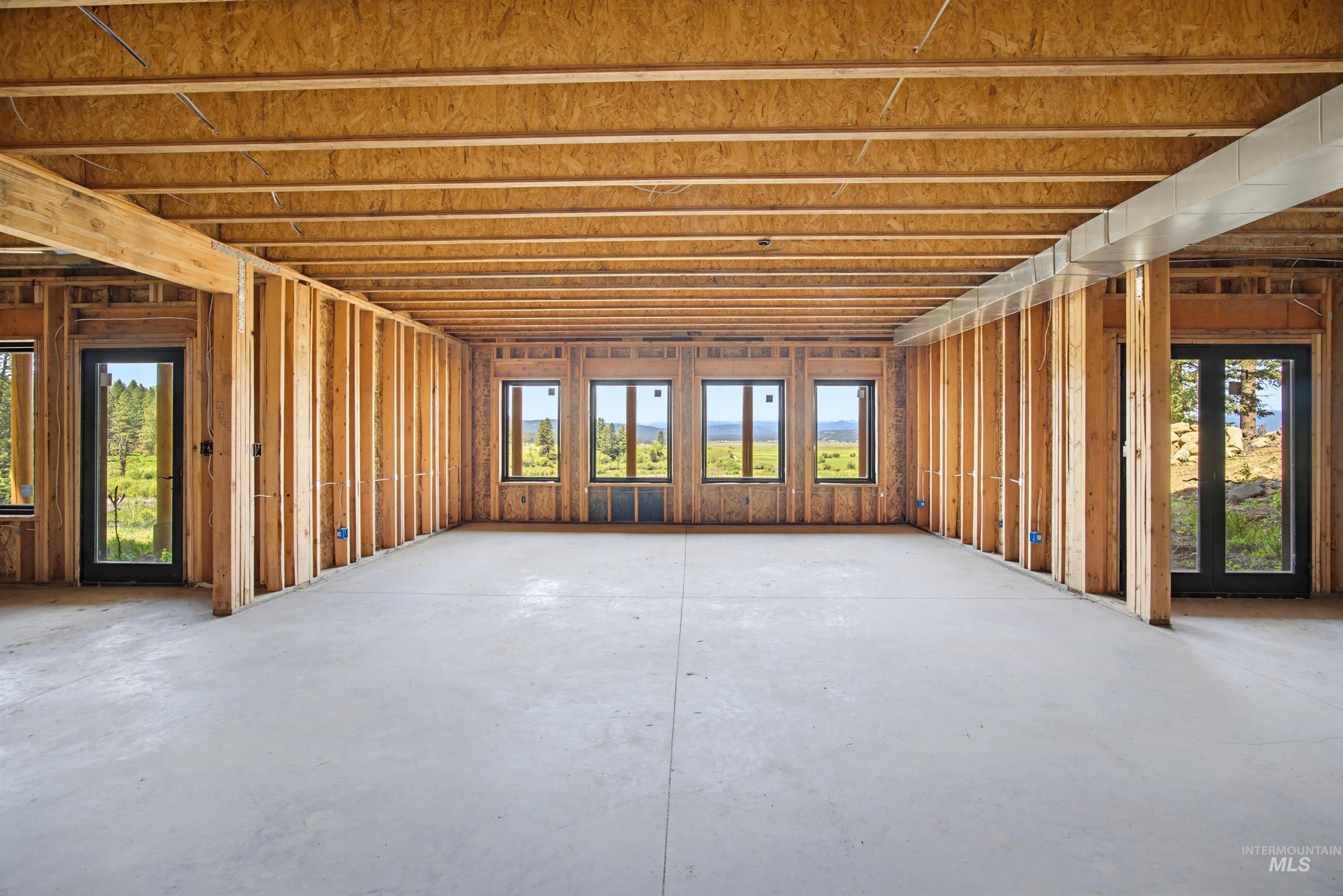 3322 Big Creek Road New Meadows, ID 83654 - Photo 23 of 50 Spacious unfinished room featuring exposed wood framing, concrete flooring, multiple windows, and two exterior doors