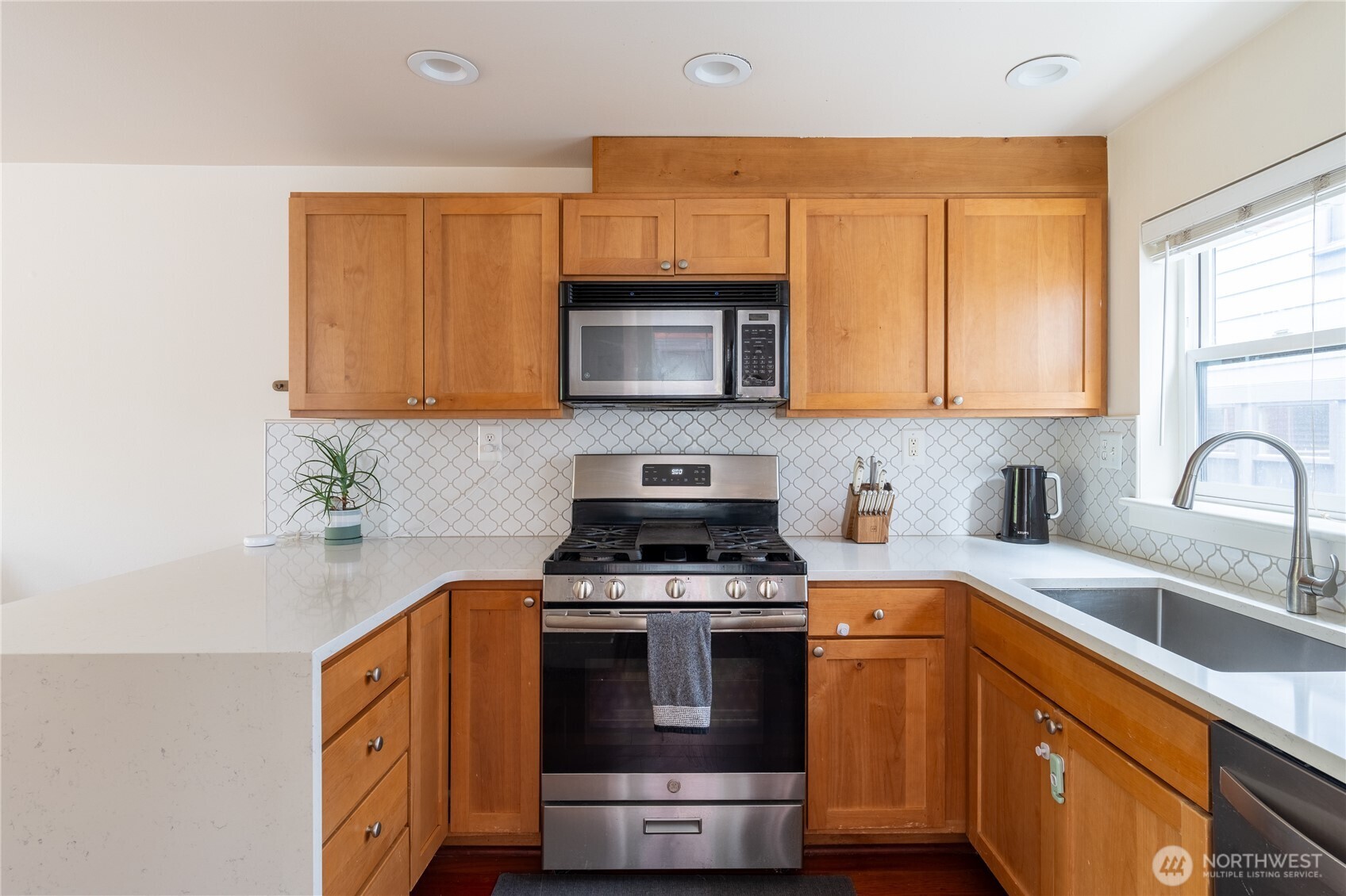 1419 Northwest 65th Street, Unit B Seattle, WA 98117 - Photo 18 of 26 a kitchen with stainless steel appliances granite countertop a stove a sink and a microwave