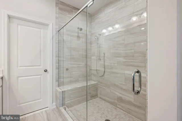 a spacious bathroom with a double vanity sink a large mirror and shower