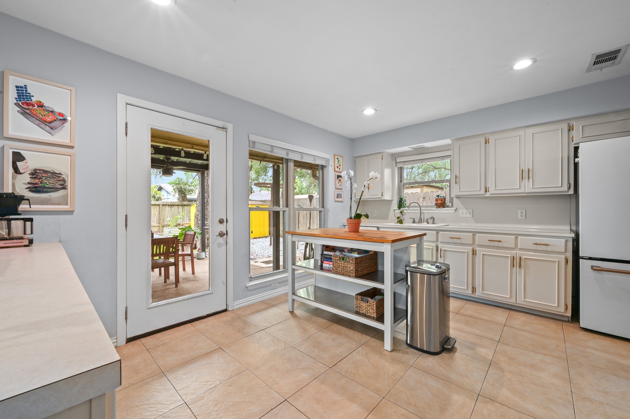 2509 Redleaf Lane Austin, TX 78745 - Photo 6 of 28 Bright kitchen featuring light cabinetry, ample counter space, tile flooring, and a glass-paneled door opening to a patio