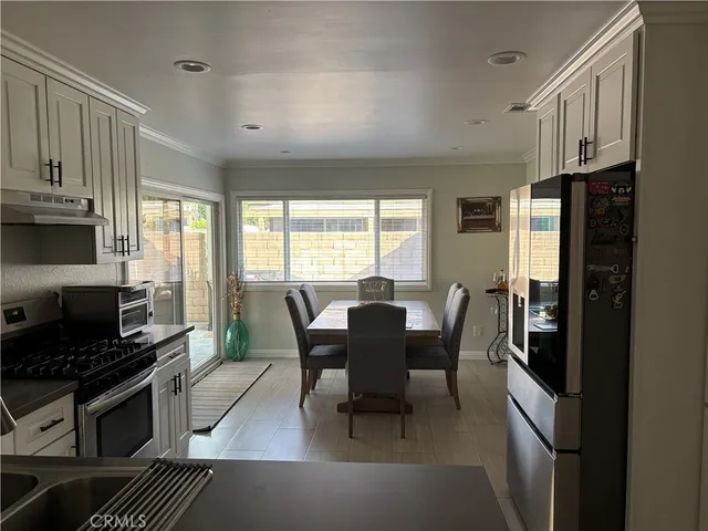 a kitchen with stainless steel appliances granite countertop a stove a refrigerator a kitchen island a table and chairs