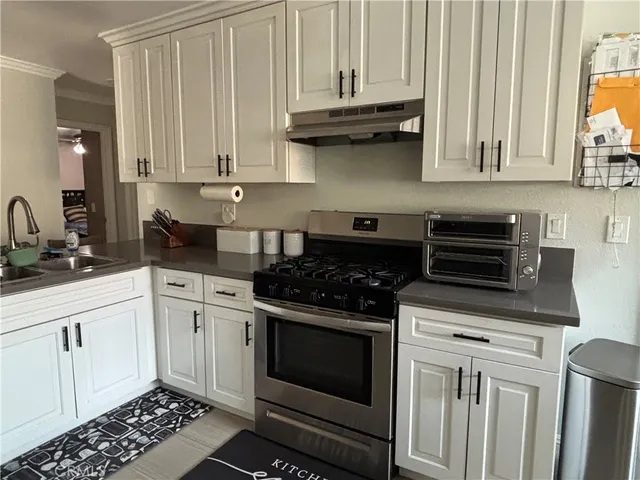 a kitchen with granite countertop white cabinets and stainless steel appliances