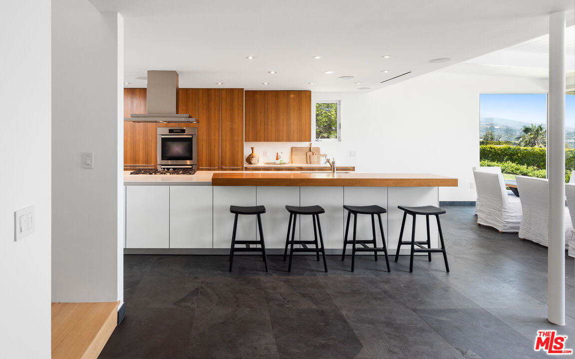 3431 Coast View Drive Malibu, CA 90265 - Photo 19 of 49 a kitchen with a table chairs sink and cabinets