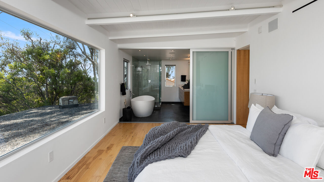 3431 Coast View Drive Malibu, CA 90265 - Photo 30 of 49 a bedroom with a bed and large windows