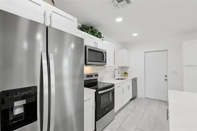 a kitchen with stainless steel appliances a sink a stove a microwave a sink a refrigerator and cabinets