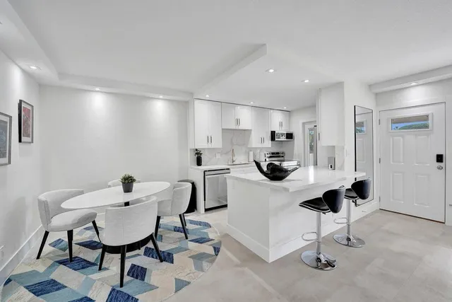 a kitchen with stainless steel appliances kitchen island a table and chairs in it