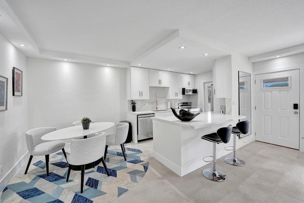 2866 Northeast 30th Street, Unit 9 Fort Lauderdale, FL 33306 - Photo 17 of 54 a kitchen with stainless steel appliances kitchen island a table and chairs in it