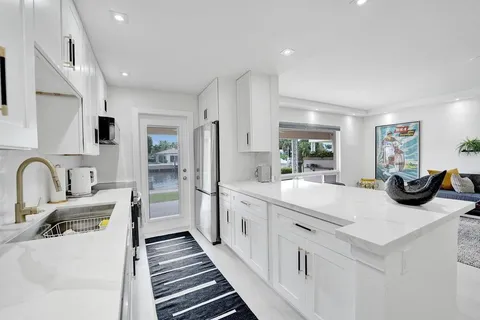 a large white kitchen with stainless steel appliances sinks a stove and white cabinets