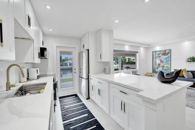 a large white kitchen with stainless steel appliances sinks a stove and white cabinets