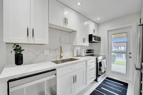 a kitchen with a sink dishwasher a stove and white cabinets