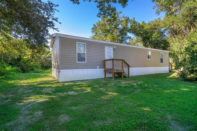 a backyard of a house with plants and large tree