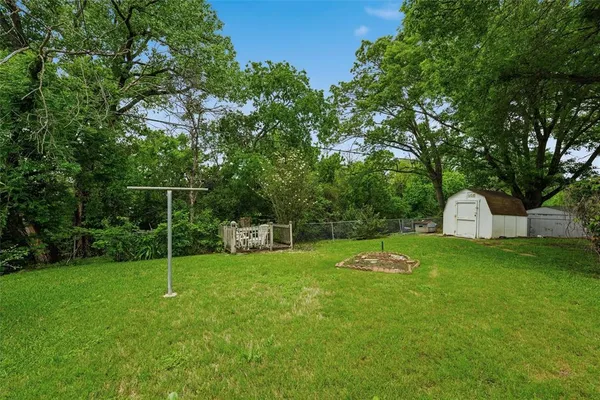 a backyard of a house with plants and large tree
