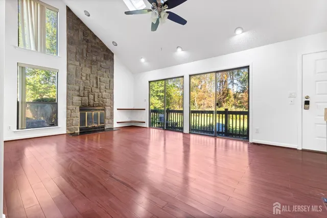 a view of an empty room with wooden floor and a fireplace