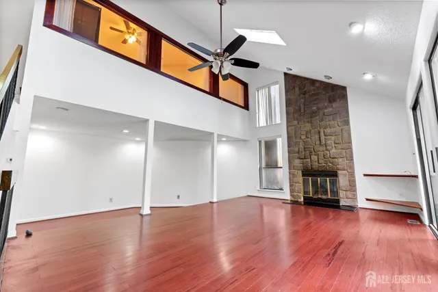 a view of an empty room with wooden floor and a ceiling fan