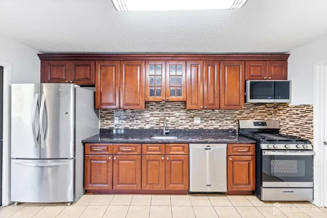 a kitchen with granite countertop a refrigerator stove top oven and sink