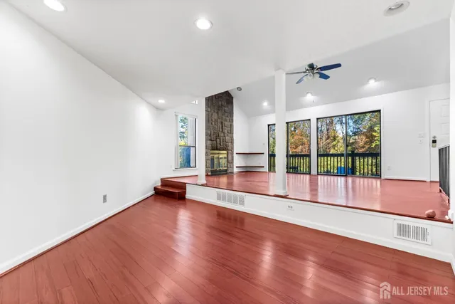 a view of empty room with wooden floor and fan