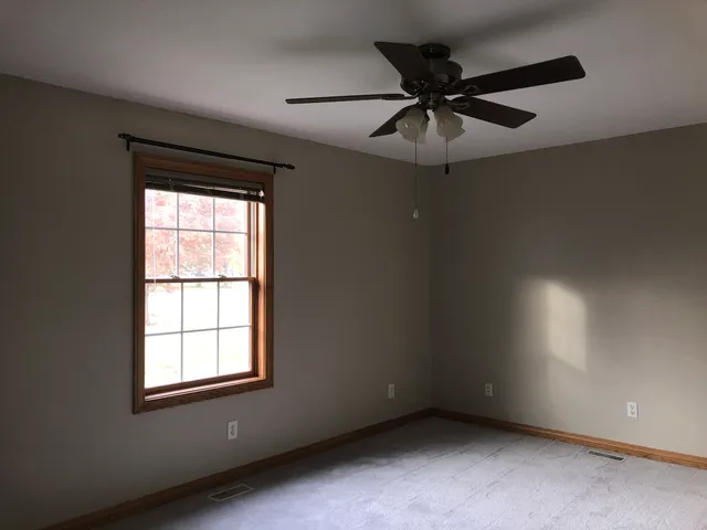an empty room with a ceiling fan and window