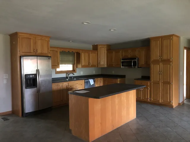 a kitchen with stainless steel appliances granite countertop a refrigerator a stove a sink and a microwave