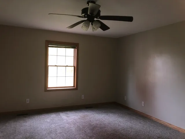 an empty room with a window and a fan