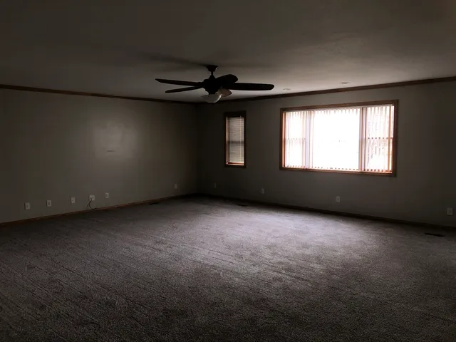 an empty room with windows and fan