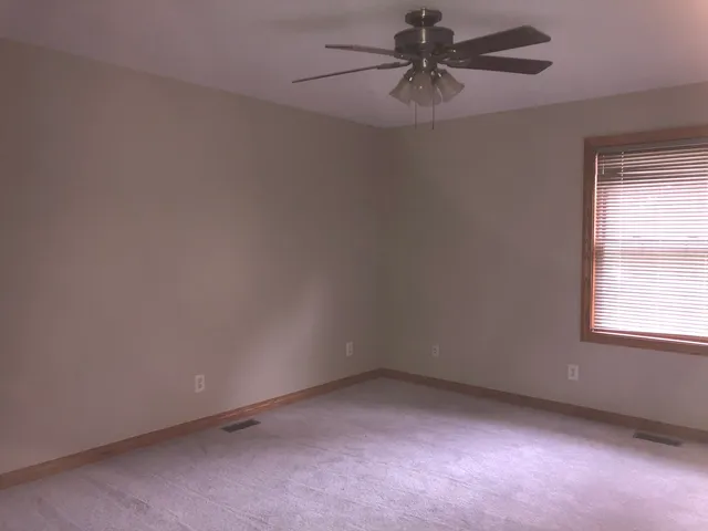 an empty room with a window and a fan