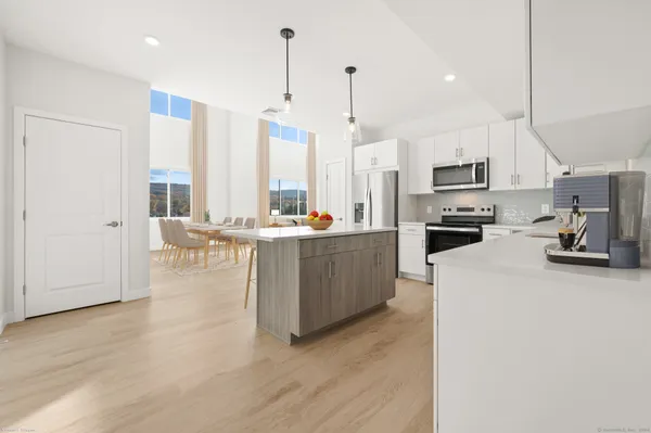 a kitchen with stainless steel appliances a refrigerator a stove a sink dishwasher a oven with white cabinets and wooden floor