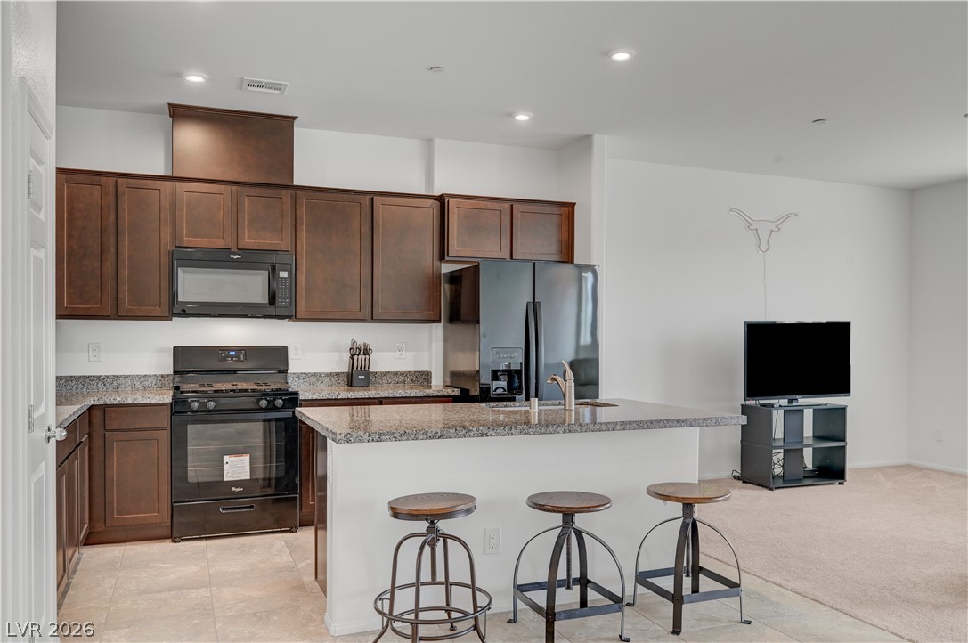 1287 Raritan Place Henderson, NV 89002 - Photo 14 of 21 A contemporary kitchen features dark cabinetry, granite countertops, and modern black appliances for a cohesive look.