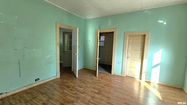 a view of an empty room with wooden floor and closet