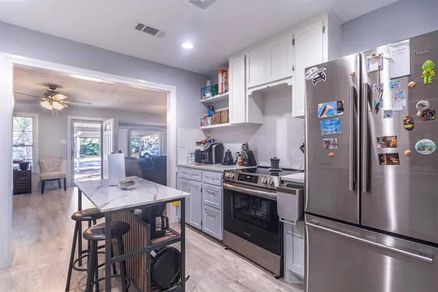 a kitchen with stainless steel appliances a stove a refrigerator and wooden floor
