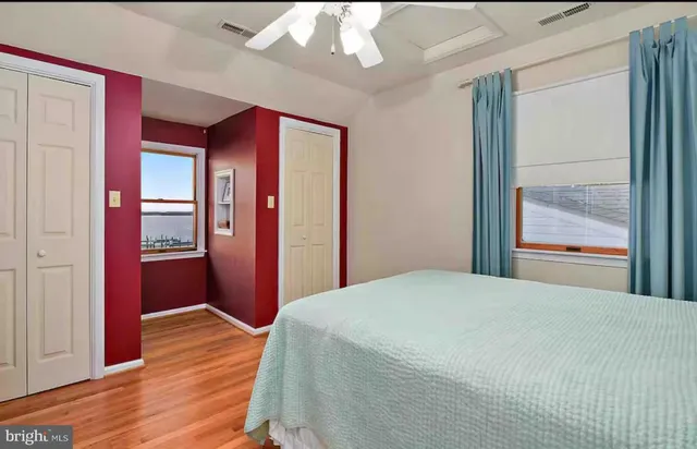 a bedroom with wooden floor closet and a bathroom