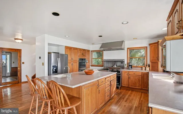 a kitchen with stainless steel appliances a stove a sink dishwasher a refrigerator with white cabinets and wooden floor