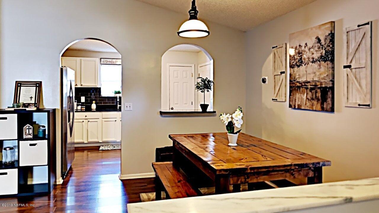 12830 Moose Road Jacksonville, FL 32226 - Photo 11 of 31 a dining room with wooden floor a chandelier a wooden table and chairs