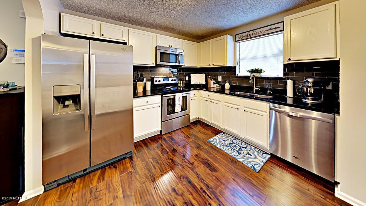12830 Moose Road Jacksonville, FL 32226 - Photo 14 of 31 a kitchen with granite countertop a refrigerator a sink dishwasher a stove and white cabinets with wooden floor