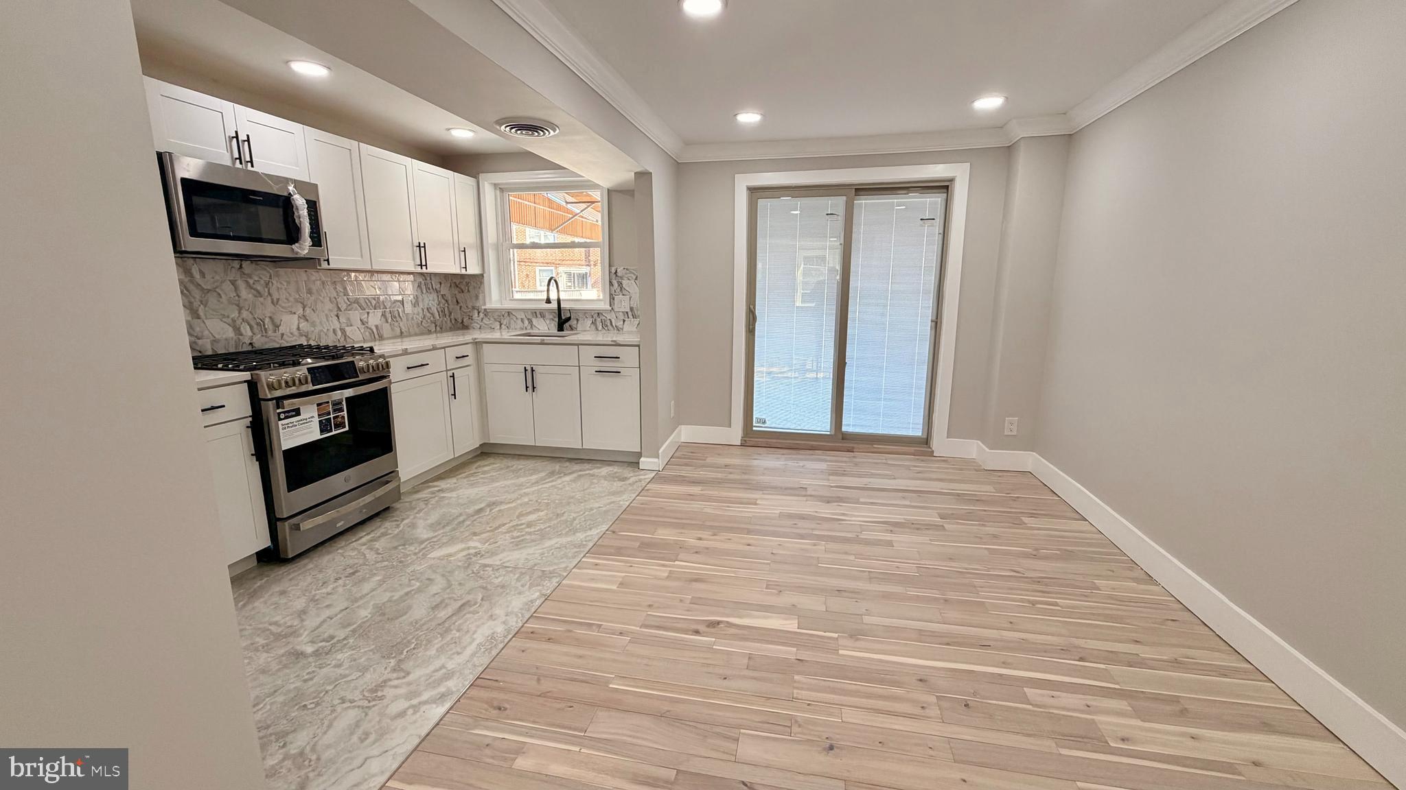 7219 Saul Street Philadelphia, PA 19149 - Photo 5 of 24 a large kitchen with cabinets wooden floor and stainless steel appliances