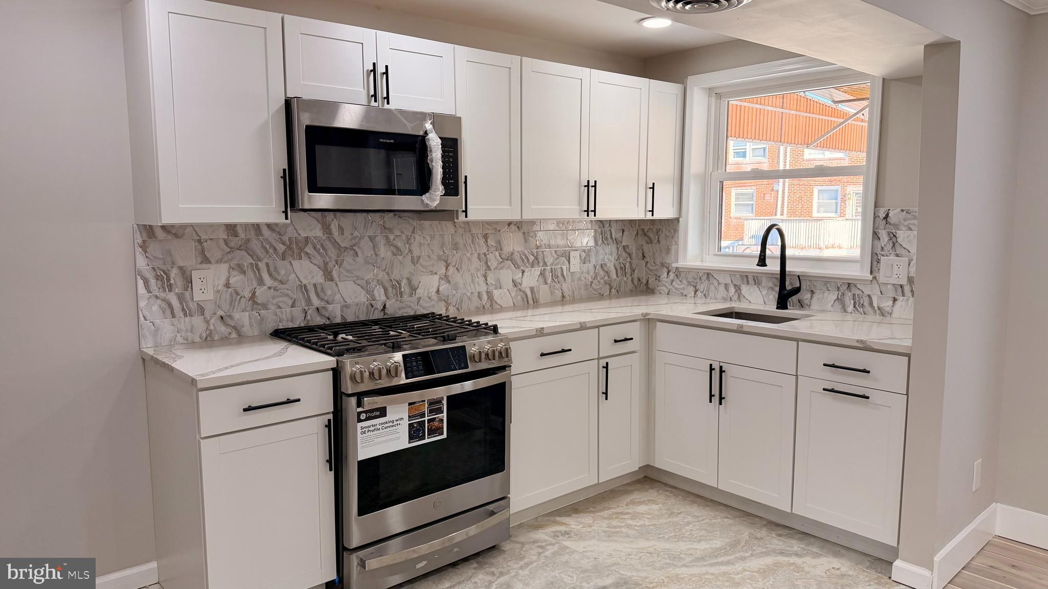 7219 Saul Street Philadelphia, PA 19149 - Photo 8 of 24 a kitchen with stainless steel appliances granite countertop white cabinets a stove top oven a sink and dishwasher