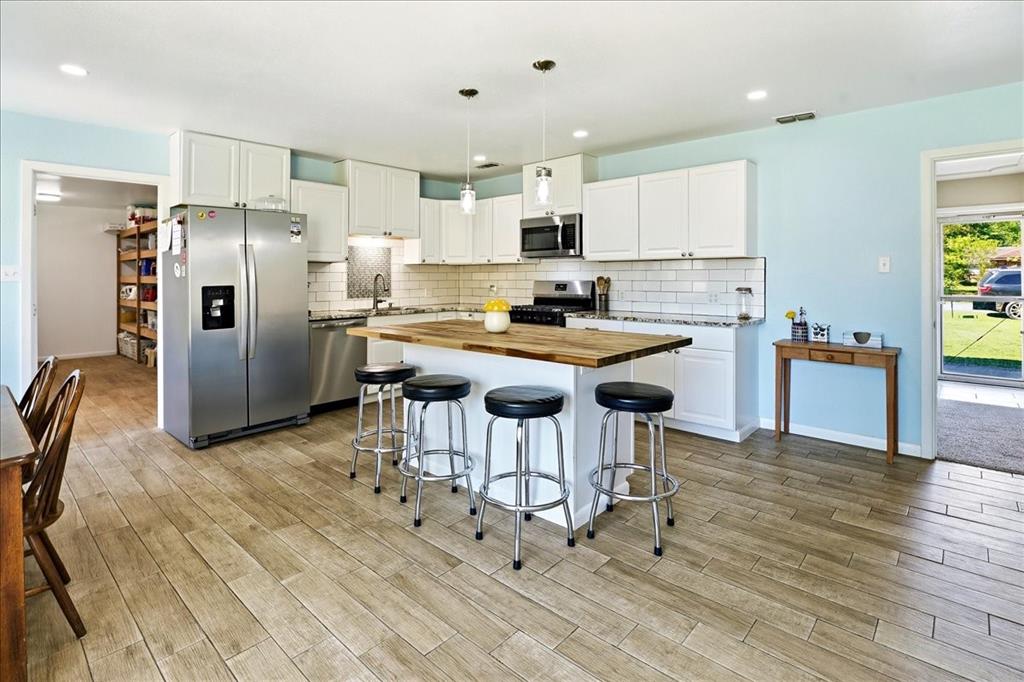 12657 Alma Street Tyler, TX 75704 - Photo 5 of 36 a kitchen with stainless steel appliances kitchen island a table chairs refrigerator and microwave