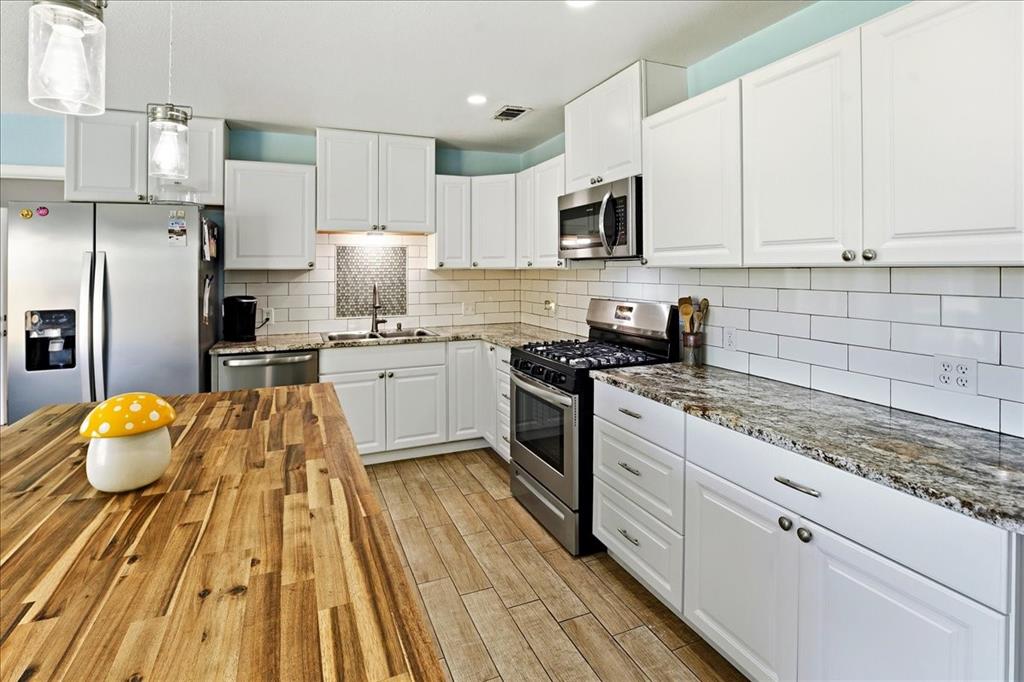 12657 Alma Street Tyler, TX 75704 - Photo 8 of 36 a kitchen with stainless steel appliances granite countertop a sink dishwasher a stove top oven a refrigerator with white cabinets and wooden floor