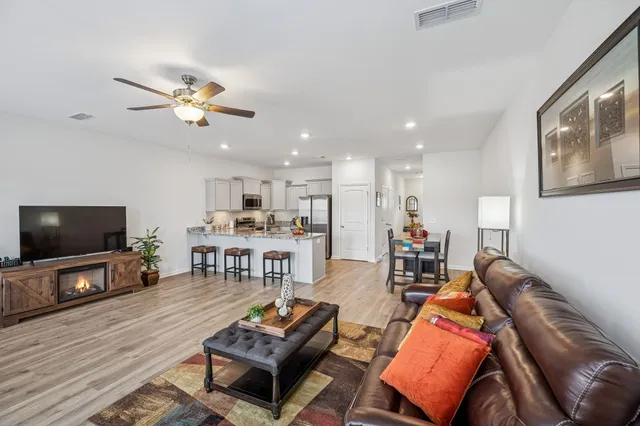 a living room with furniture a flat screen tv and kitchen view