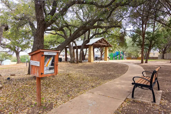 a park view with a bench under large trees
